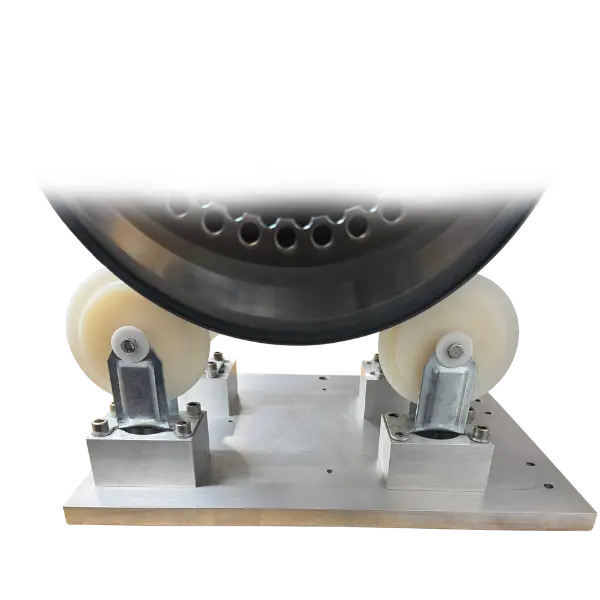 A close-up of a part fixture with two beige plastic rollers mounted on a silver aluminum base, with a circular engine spool above them, isolated on a white background.