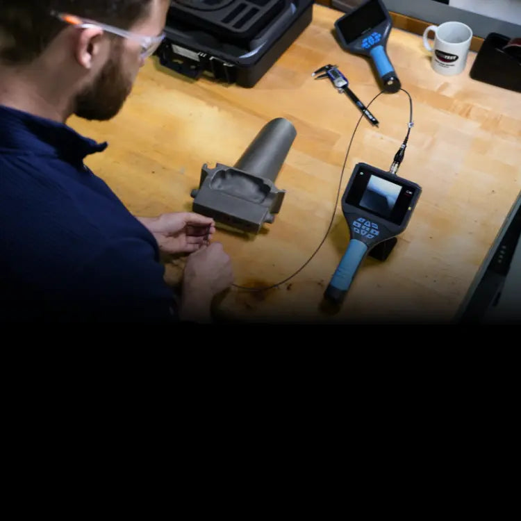 Inspector using a video borescope on a turbine part