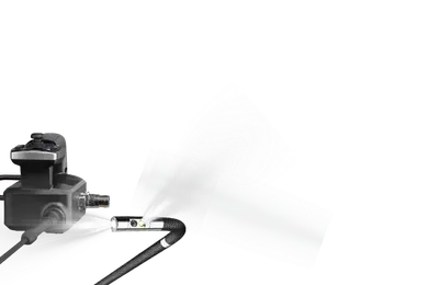A close-up of a black and silver borescope handle, shown against a plain white background with a faint spray mist effect.